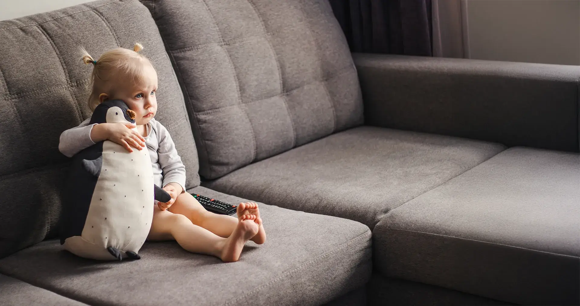 little girl hugging toy penguin sofa